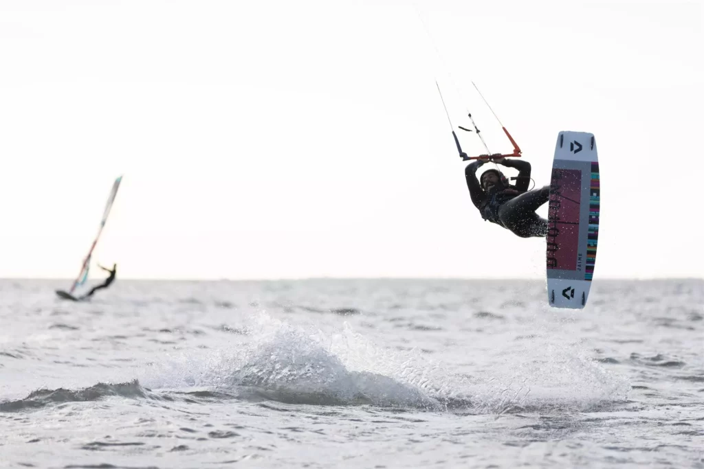 saut en kitesurf à Dakhla au Maroc avec un planchiste à l'arrière-plan.