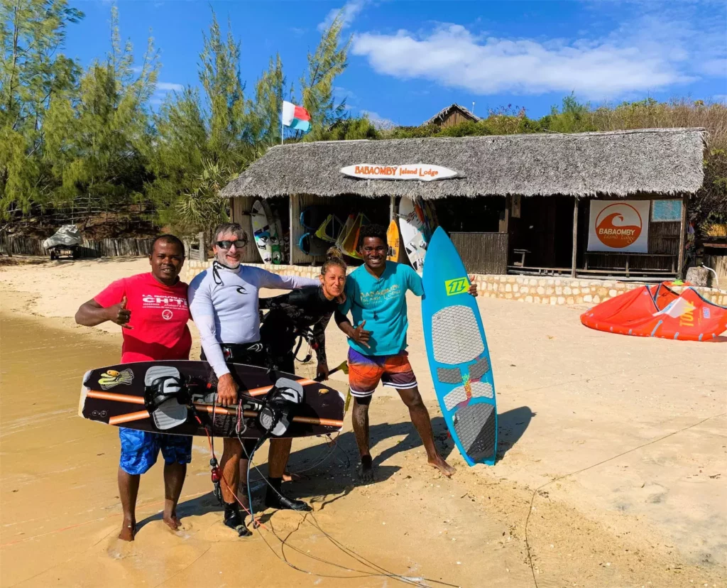 Groupe de kitesurfeurs posant avec leur matériel devant un club de glisse à Madagascar.