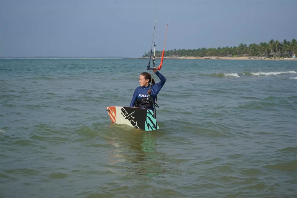 Une kitesurfeuse souriante dans l'eau avec sa planche à Kalpitiya au Sri Lanka.