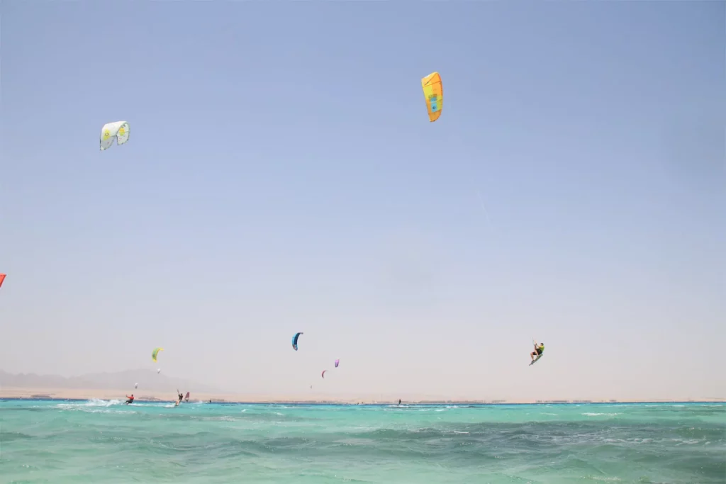 Plusieurs voiles de kitesurf colorées volent dans le ciel bleu au-dessus d'une mer turquoise à Safaga en Égypte.
