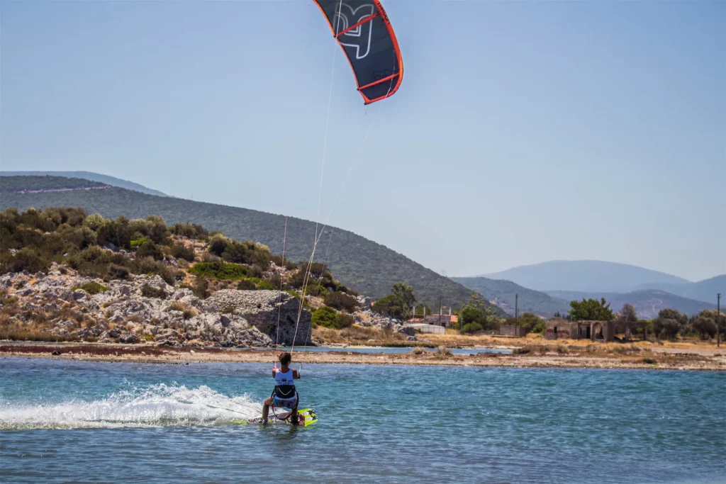 Pratique du kitesurf sur une eau calme à Urla en Turquie avec des collines en arrière-plan.
