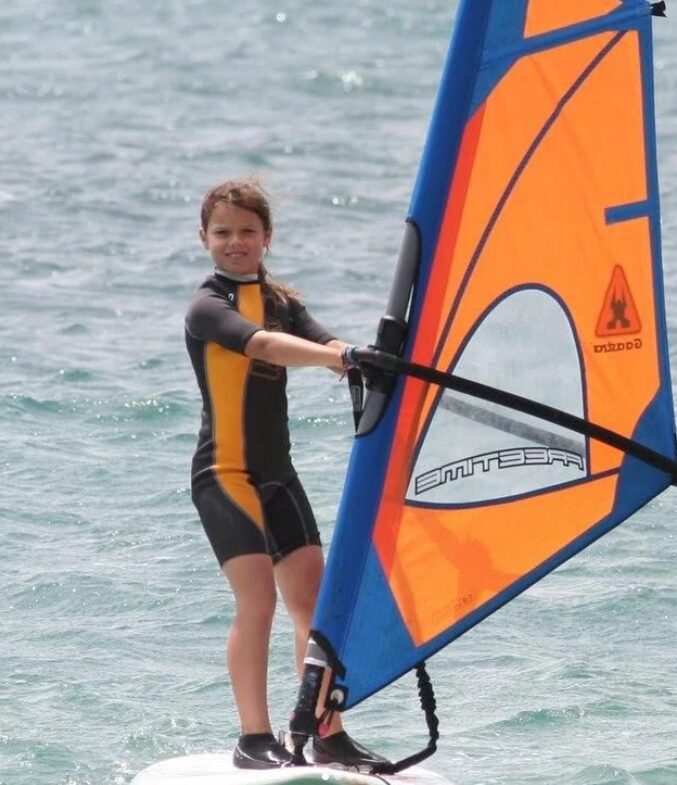 Une jeune fille en combinaison navigue en planche à voile (windsurf) sur une eau calme Lanzarote