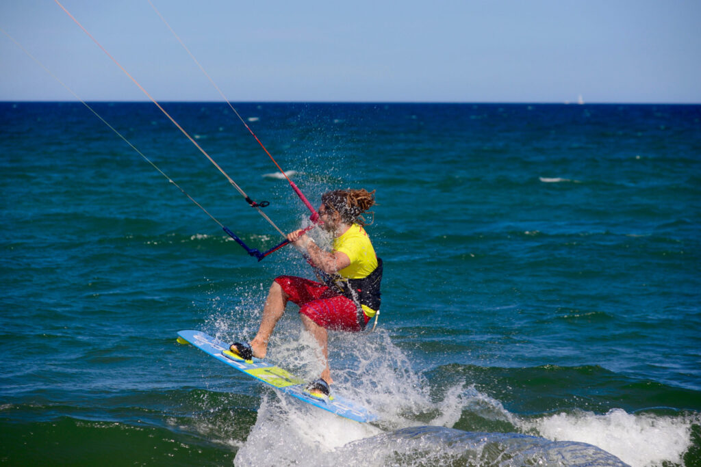 Un kitesurfeur en short rouge et t-shirt jaune navigue de manière dynamique en créant des éclaboussures d'eau en espagne tarifa et rosas